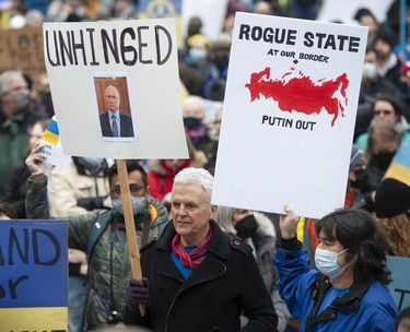 People hold signs and flags as thousands gather for a rally in support of the people of Ukraine, in Vancouver, on Saturday, February 26, 2022.