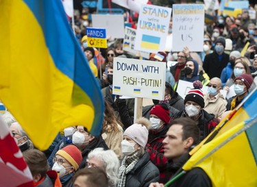 People hold signs and flags as thousands gather for a rally in support of the people of Ukraine, in Vancouver, on Saturday, February 26, 2022.