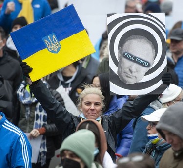 People hold signs and flags as thousands gather for a rally in support of the people of Ukraine, in Vancouver, on Saturday, February 26, 2022.