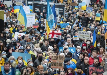 People hold signs and flags as thousands gather for a rally in support of the people of Ukraine, in Vancouver, on Saturday, February 26, 2022.