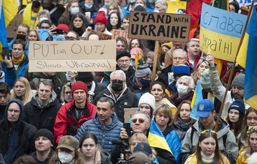 People hold signs and flags as thousands gather for a rally in support of the people of Ukraine, in Vancouver, on Saturday, February 26, 2022.
