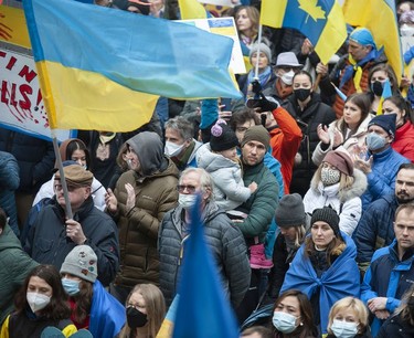 People hold signs and flags as thousands gather for a rally in support of the people of Ukraine, in Vancouver, on Saturday, February 26, 2022.