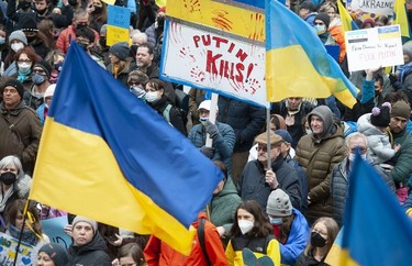 People hold signs and flags as thousands gather for a rally in support of the people of Ukraine, in Vancouver, on Saturday, February 26, 2022.