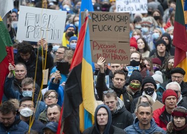People hold signs and flags as thousands gather for a rally in support of the people of Ukraine, in Vancouver, on Saturday, February 26, 2022.