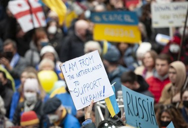 People hold signs and flags as thousands gather for a rally in support of the people of Ukraine, in Vancouver, on Saturday, February 26, 2022.