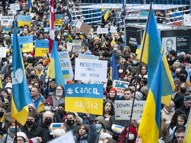 People hold signs and flags as thousands gather for a rally in support of the people of Ukraine, in Vancouver, on Saturday, February 26, 2022.