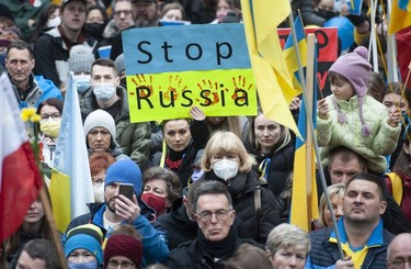 People hold signs and flags as thousands gather for a rally in support of the people of Ukraine, in Vancouver, on Saturday, February 26, 2022.