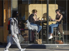 People sitting at coffee shops on Main street in Vancouver, BC, February 15, 2022.