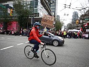 VANCOUVER, C.-B. – 04 FÉVRIER: Un cycliste tient une pancarte de protestation alors qu'il descend la rue Burrard alors que des milliers de personnes se sont rassemblées au centre-ville lors d'une manifestation Covid à Vancouver le 5 février 2022.