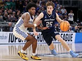 Doug Edert of the Saint Peter's Peacocks drives against Sahvir Wheeler of the Kentucky Wildcats during the first-round game of the NCAA Men's Basketball Tournament at Gainbridge Fieldhouse on March 17 in Indianapolis.