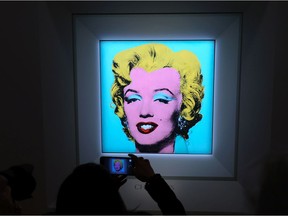 A guest takes a photo during Christie's announcement that they will offer Andy Warhol's Shot Sage Blue Marilyn painting of Marilyn Monroe at Christie's on March 21, 2022 in New York City.