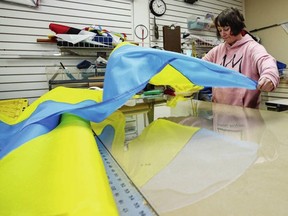 Seamstress Freyja Zazu works on Ukranian flags for Victoria's Flag Shop on Monday. The sewing machine hasn't stopped at the Flag Shop since Russians invaded Ukraine last week.