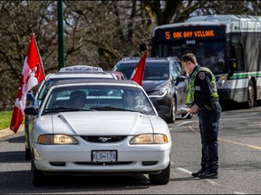 Victoria police officers check vehicles at a roadblock on Superior Street near Douglas Street as police closed off James Bay to all but local traffic on Saturday, March 19, 2022, ahead of expected protests at the legislature.