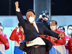South Korea's new president-elect Yoon Suk Yeol (C) of the main opposition People Power Party gestures to his supporters as he is congratulated outside the party headquarters in Seoul on March 10, 2022.