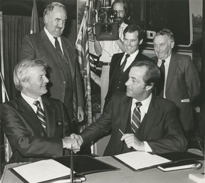 Ontario Prime Minister Bill Bennett (left) is shaking hands with BC Prime Minister Bill Bennett after Bennett has signed a contract to purchase a high-speed transportation system developed for Vancouver in Ontario. Looking (from left) is James Snow, Director of Transport in Ontario, Bill Vander Zarm, Minister of State for British Columbia, and Ray Perrault, Liberal Senator. This system is known as SkyTrain.