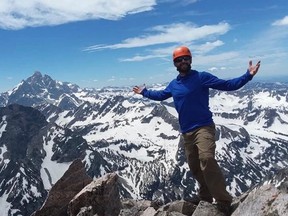Photo of man with arms outstretched on mountaintop
