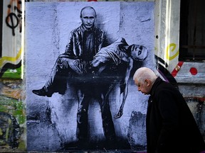 A resident walks past mural depicting Russian President Vladimir Putin holding his own body in Sofia, on March 15, 2022.