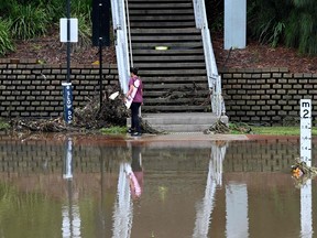 A woman makes her way next to spillover from the flooded Parramatta river at the ferry wharf in Sydney on February 23, 2022.