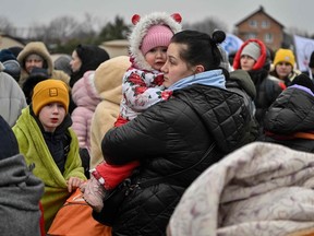 Refugees wait in freezing cold temperatures to get on a bus after crossing the Ukrainian border into Poland.