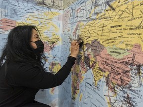 Larah Luna of the Vancouver Art Gallery stamps a message of solidarity on Ukraine, part of a massive world map at the gallery that is part of the Yoko Ono: Growing Freedom exhibit this week.