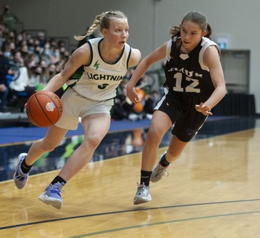 Langley Christian Lightning's Sydney Bradshaw tries to drive the ball downcourt while being guarded by St. Michaels University School Blue Jags' Avery Geddes.