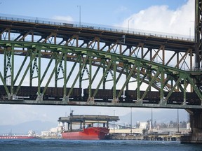 Pictured is a cargo ship as seen from Burrard Inlet March 8, 2022. Foreground Second Narrows rail and road bridges.