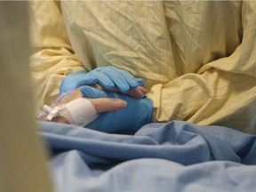 An ICU nurse holds a COVID-19 patient's hand in the ICU at Surrey Memorial Hospital Friday, June 4, 2021.