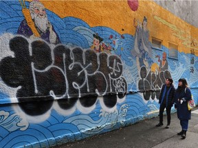 Artists Sean Kao and Catherine Yi in front of a destroyed mural in Chinatown.