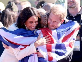 Prince Harry, Duke of Sussex and Meghan, Duchess of Sussex hug Lisa Johnston of Team United Kingdom at the Athletics Competition during day two of the Invictus Games The Hague 2020 at Zuiderpark on April 17, 2022 in The Hague, Netherlands.
