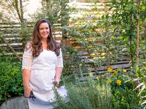 Garden expert Stephanie Rose with her herb garden featuring rosemary and a yuzu tree in front of a vertical-growing Wintercreeper (Euonymus x fortunei 'Tricolor') that has been espaliered on the cedar structure in her garden.