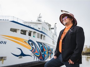 B.C. Ferries has unveiled its latest vessel, the Salish Heron, adorned with the art of Coast Salish artist Maynard Johnny Jr., pictured here with the vessel on April 15, 2022 in Richmond, B.C.