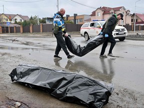 Communal workers carry body bags in the town of Bucha, not far from the Ukrainian capital of Kyiv on April 3, 2022.