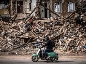 A man rides a scooter past the rubble of a destroyed building in the eastern Ukraine city of Kharkiv on april 2, 2022, as Ukraine said today Russian forces were making a 