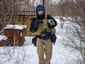 Ukrainian photographer Maksim Levin carries a cat near the line of separation from Russian-backed separatists in Donetsk region, Ukraine Jan. 25, 2022.