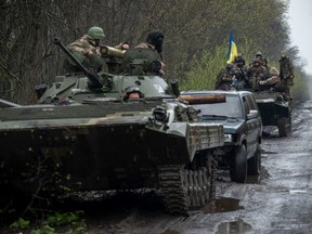 Ukrainian servicemen sit atop an armoured fighting vehicle, as Russia’s attack on Ukraine continues, at an unknown location in eastern Ukraine, in this handout picture released April 19, 2022.
