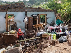 A member South African Police Services (SAPS) Search and Rescue Unit guide their sniffer dog during search efforts to locate ten people who are unaccounted for from area of KwaNdengezi township outside Durban on April 15, 2022 after their homes were swept away following the devastating rains and flooding.
