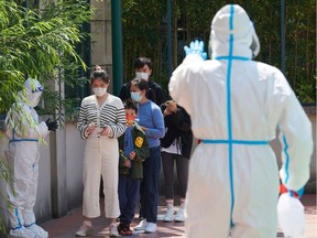 Community volunteers wearing personal protective equipment guide residents queuing to get tested for the Covid-19 coronavirus in a compound during a Covid-19 lockdown in Pudong district in Shanghai on April 17, 2022.