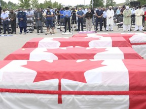 Trauernde beten, während in kanadische Flaggen gehüllte Schatullen bei einer Beerdigung für die vier muslimischen Familienmitglieder aufgereiht werden, die bei einem tödlichen Fahrzeugangriff im Islamischen Zentrum von Südwest-Ontario in London, Ontario, am Samstag, dem 12. Juni 2021, getötet wurden. Talat Afzaal , 74, ihr Sohn Salman Afzaal, 46, seine Frau Madiha Salman, 44, und ihre 15-jährige Tochter Yumna Salman starben alle letzten Sonntagabend bei einem Spaziergang, nachdem ein Mann in einem Lastwagen sie mit dem, was die Polizei hat, heruntergefahren hatte als vorsätzlicher Angriff bezeichnet, weil sie Muslime waren.