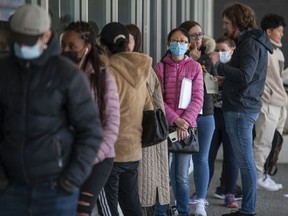 Dozens of people line up outside the Service Canada office on W. Broadway in Vancouver on Friday.