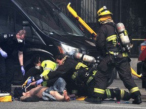 Three types of cancer are being added to B.C.'s existing list of cancers frequently suffered by firefighters that are covered by workers' compensation. Paramedics and fire crews work on a patient during a four alarm fire at the Winters Residence at 203 Abbott St in Vancouver, BC., on April 11, 2022.