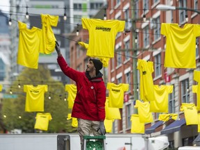 Yousef Hasan hangs Sun Run t-shirts in Helmken Plaza in Vancouver on April 14, 2022.