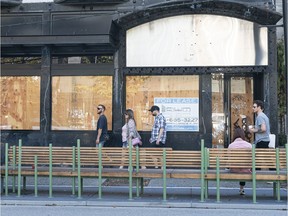 Pedestrians walk past an empty a storefront on Robson Street in Vancouver.