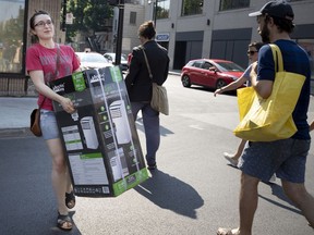 A woman carries an air conditioner to the bus stop during a heat wave in Montreal in 2018.