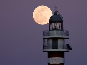 A full moon known as the flower moon rises behind the Arinaga lighthouse  on the island of Gran Canaria, Spain, before a lunar eclipse on Sunday night that will be visible to billions around the globe.