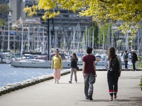 People enjoy the sunny weather along the Yaletown seawall in Vancouver.