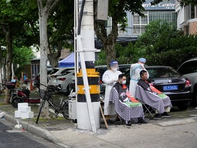 Residents get haircuts on a closed street during lockdown amid the COVID-19 pandemic, in Shanghai, China, Friday, May 20, 2022.