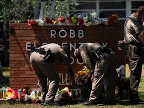 Two Texas Troopers light a candle at Robb Elementary School in Uvalde, Texas, Wednesday, May 25, 2022.