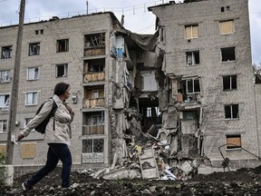 A woman walks by a destroyed apartment building in Bakhmut in the eastern Ukranian region of Donbass on May 22, 2022, amid Russian invasion of Ukraine. (Photo by ARIS MESSINIS / AFP)