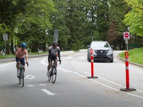 Ein Auto und zwei Radfahrer auf ihren Spuren im Stanley Park am 24. Mai 2022.