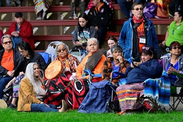 Evelyn Camille (holding the feather) listens to speakers at a memorial event marking the first anniversary of the discovery of unmarked Indigenous child graves at the Tk'emlups Pow Wow Arbour in Kamloops, B.C., May 23, 2022.